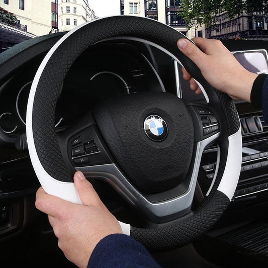 Steering wheel with BMW logo held by a person inside a car.