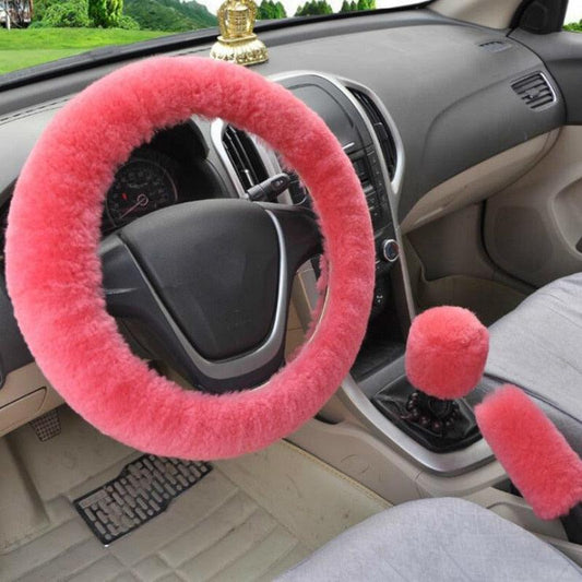 Car interior with a pink fuzzy steering wheel cover and gear shift cover.