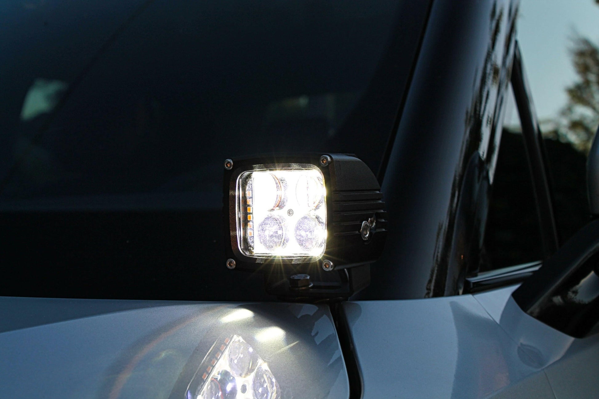 LED work light attached to a vehicle's side mirror with a blurred background