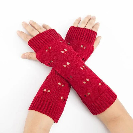 Red knitted arm warmers with heart patterns on a white background