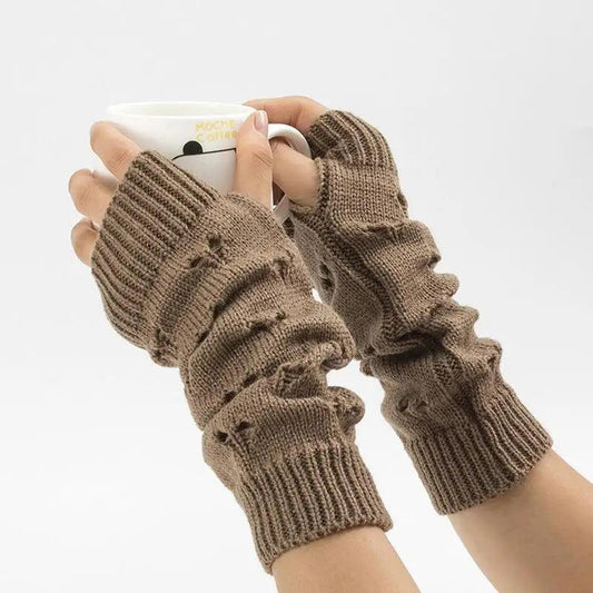 Brown knitted arm warmers worn by a person holding a mug on a white background